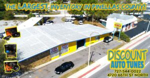 Aerial Drone Shot of Discount Auto Tunes yellow building black car, parked parking lot